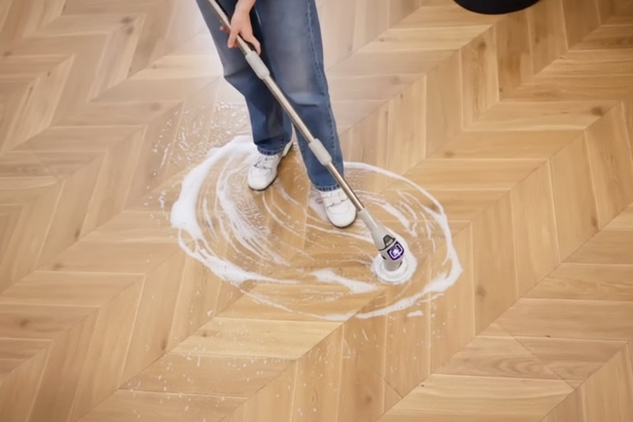Person cleaning a wooden floor with an electric brush
