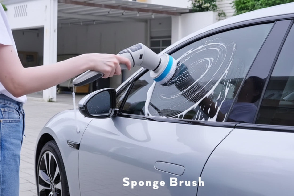 Person using a sponge brush to clean a car window with soapy water.